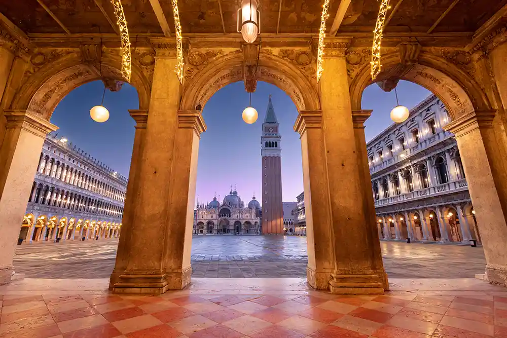 : Enchanting view of St. Mark's Square at sunset, with the Basilica and Bell Tower glowing in golden evening light