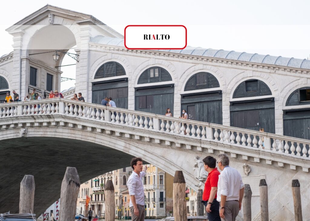 The Rialto Bridge, one of Venice's most iconic landmarks, bustling with tourists on a bright day.