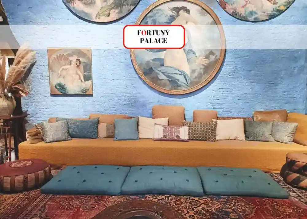 A cozy lounge corner inside the Fortuny Palace in Venice, where antique artworks, colorful cushions, and refined tapestries evoke a unique mix of art, elegance, and creative spirit.