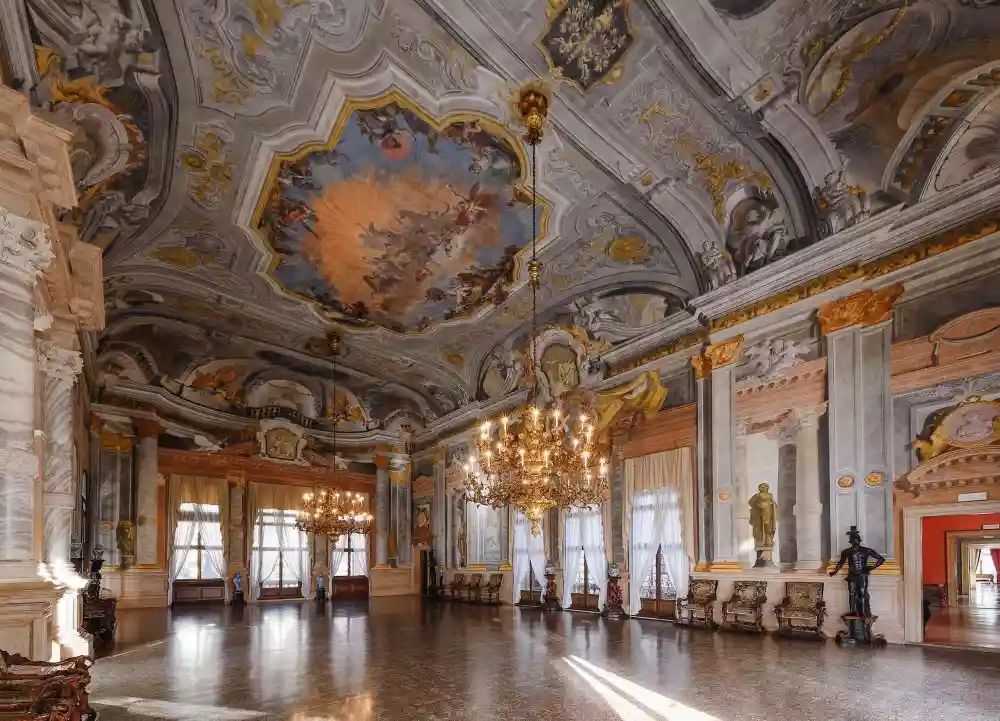 A breathtaking view of a grand Baroque hall in Venice, adorned with majestic chandeliers, richly decorated ceilings, and golden statues—an immersive journey through the splendor of Venetian nobility.