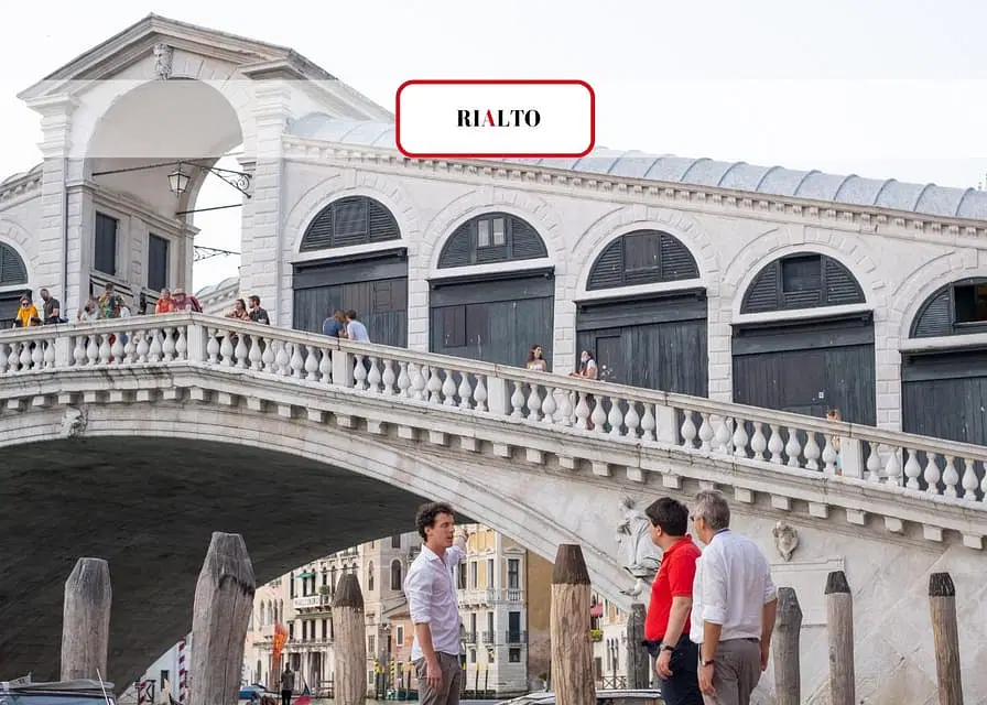 Vista del Ponte di Rialto con turisti in primo piano e persone che passeggiano lungo la sommità